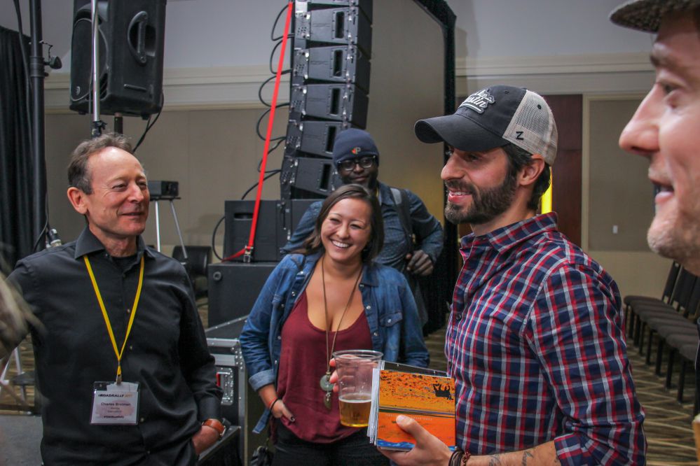 Music Supervisor Frank Palazzolo has a handful of music from TAXI members, a half-full beer, and a big smile on his face when he runs into friends Charles and Julia Brotman after his panel at the Rally.