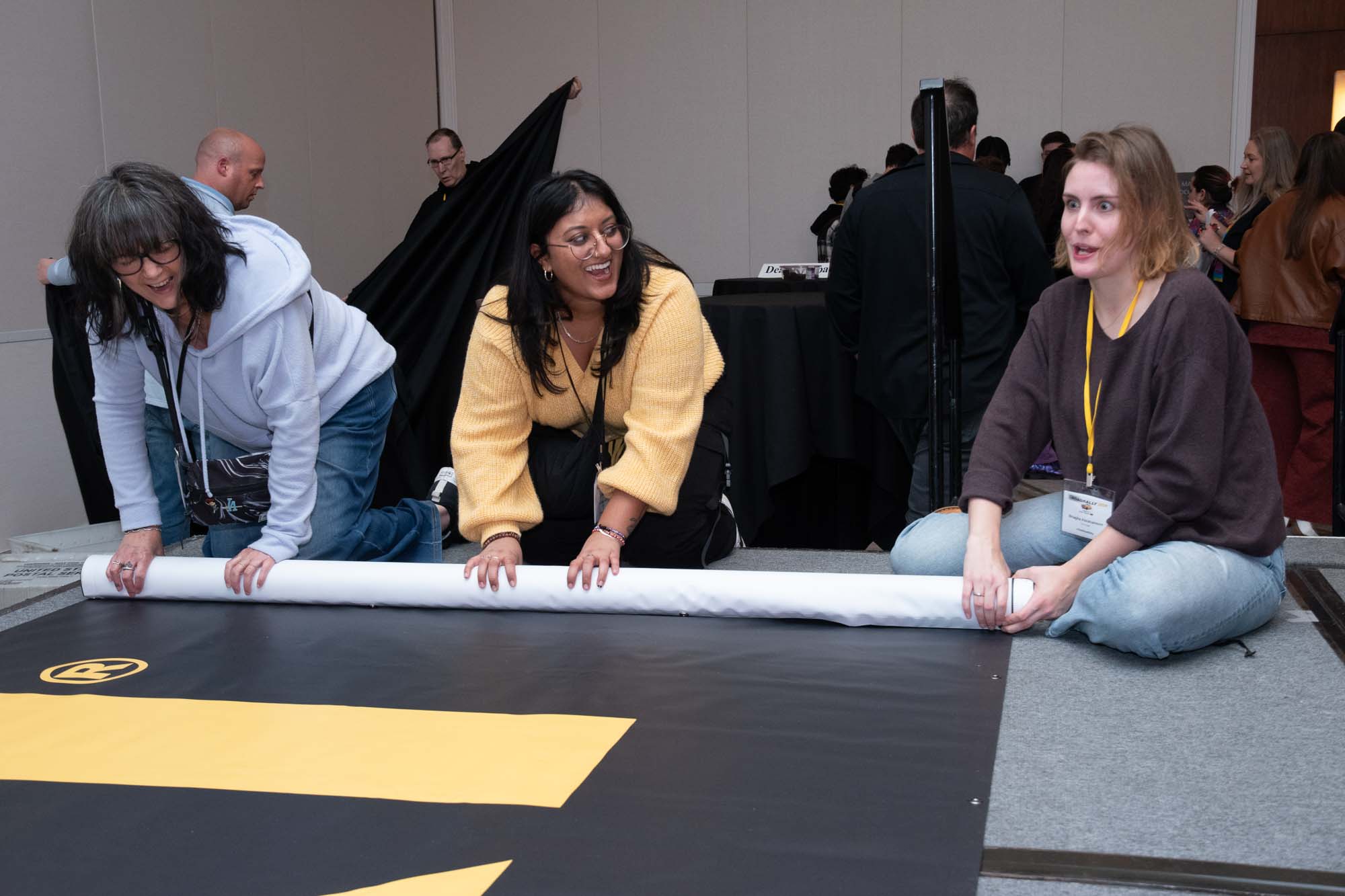 TAXI staff member Briagha Abrahamson (right) seems a bit surprised to find out that the boss wants his “priceless” Road Rally ballroom/main stage banner rolled up inside-out rather than outside-in. Her colleagues Liz Cohen (left) and Ashmita Deo (center) clearly thought it was hilarious.